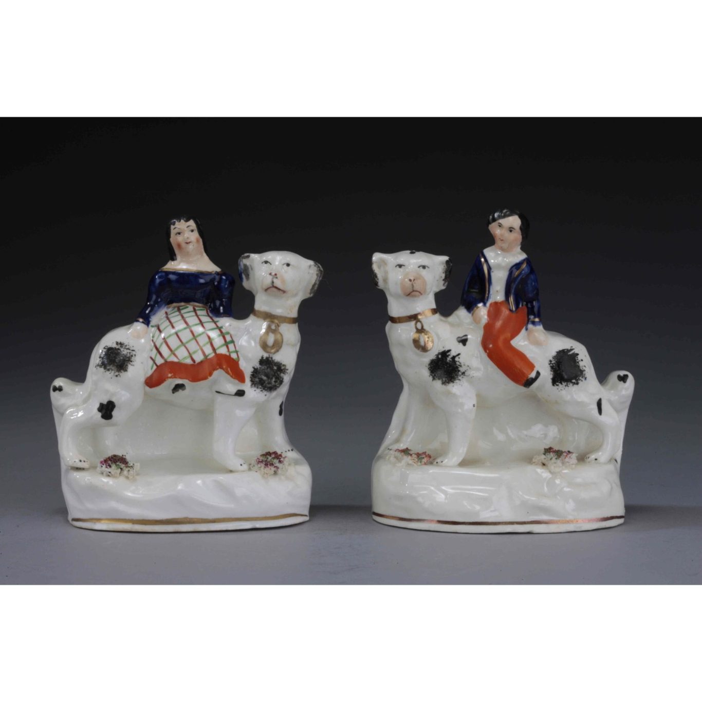 Pair of antique Staffordshire figures of children sitting on dogs