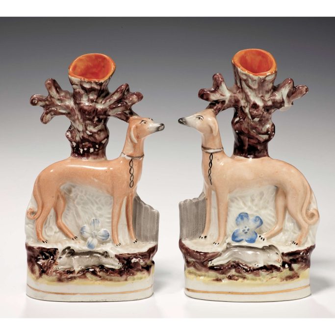 Find a pair of antique Staffordshire standing whippets with hares at their feet for sale.